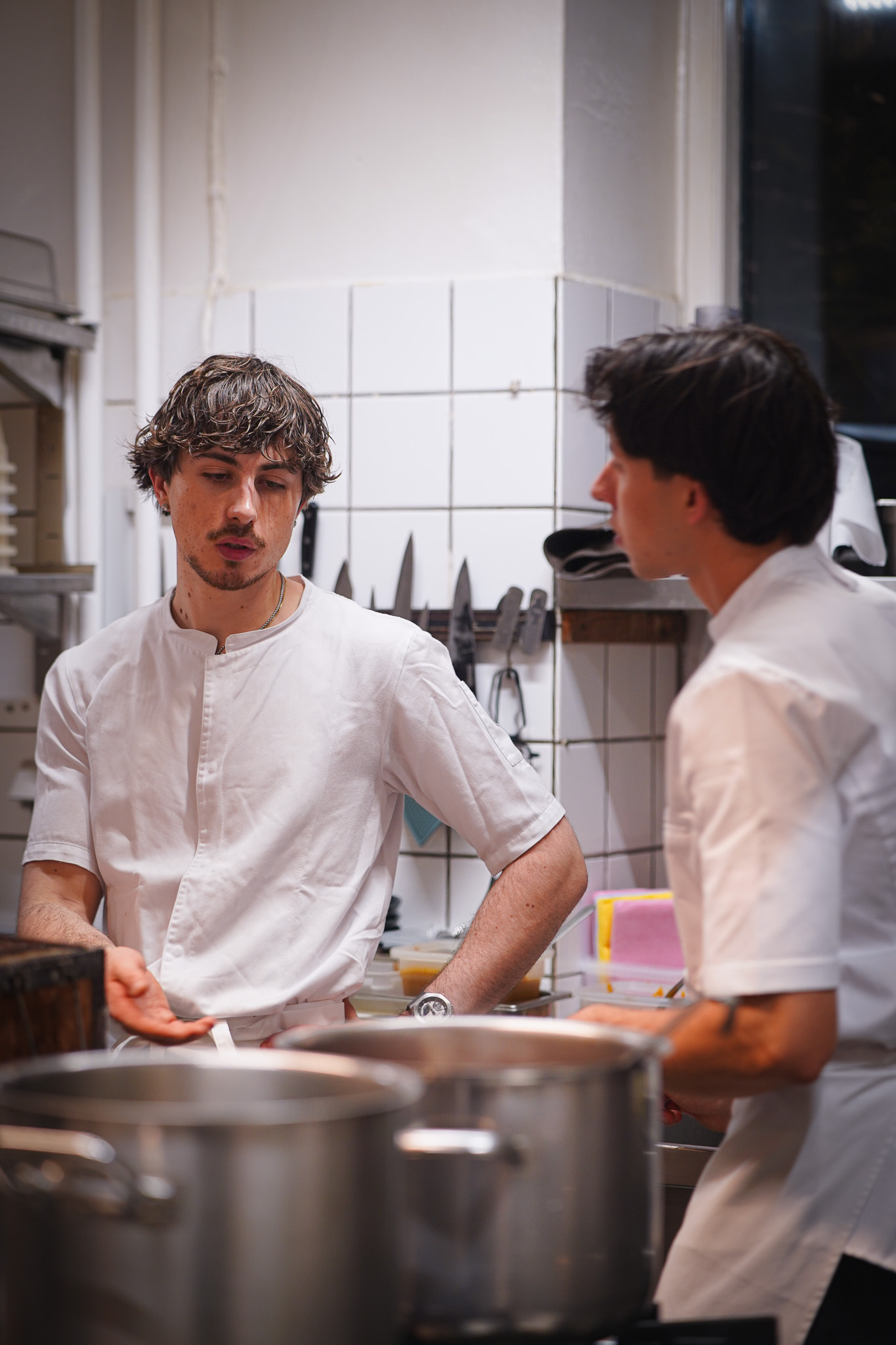 Two chefs conferring over stockpots in the kitchen