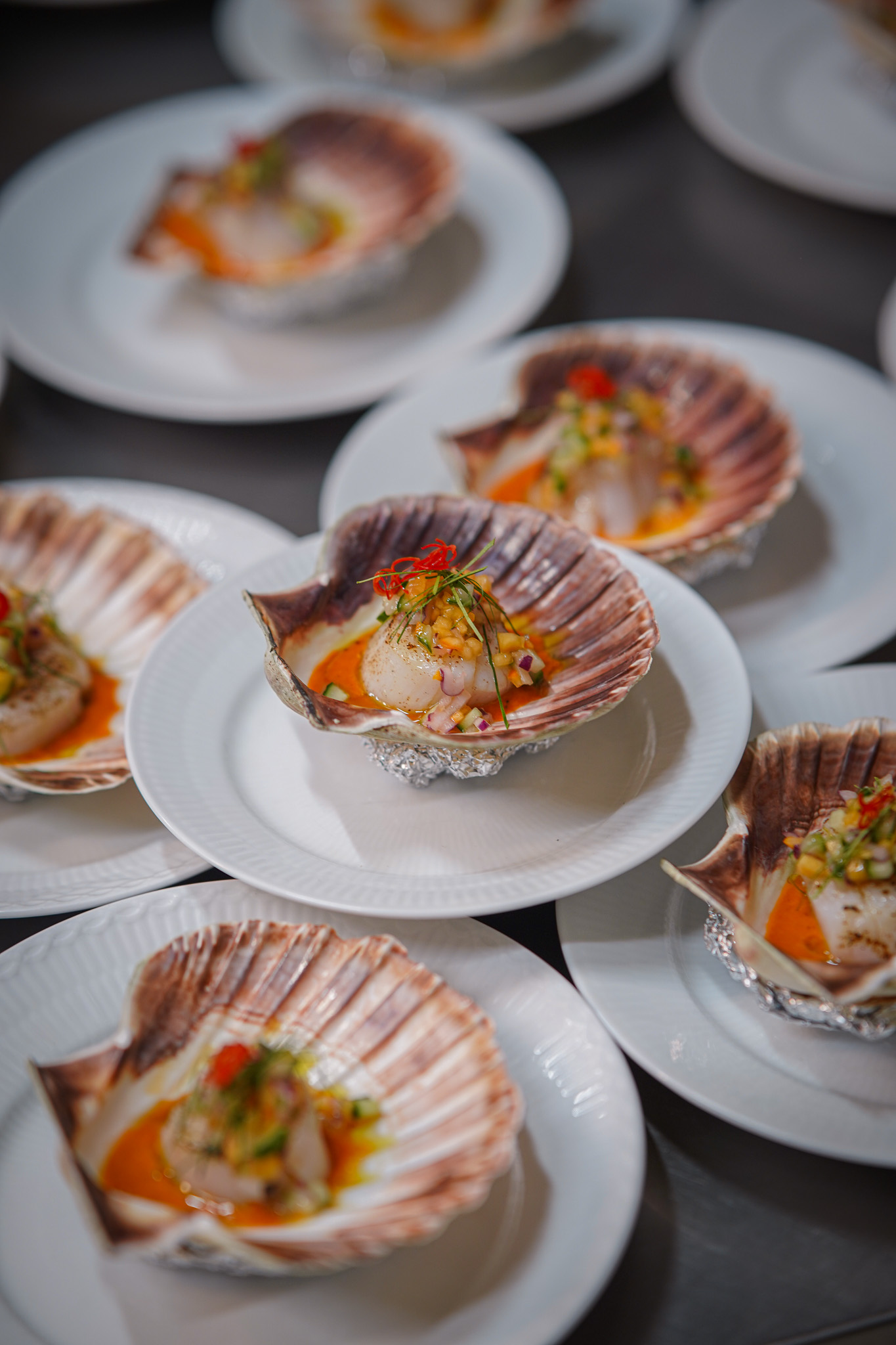 Plated scallop shells with citrus garnish, arranged for a private dinner